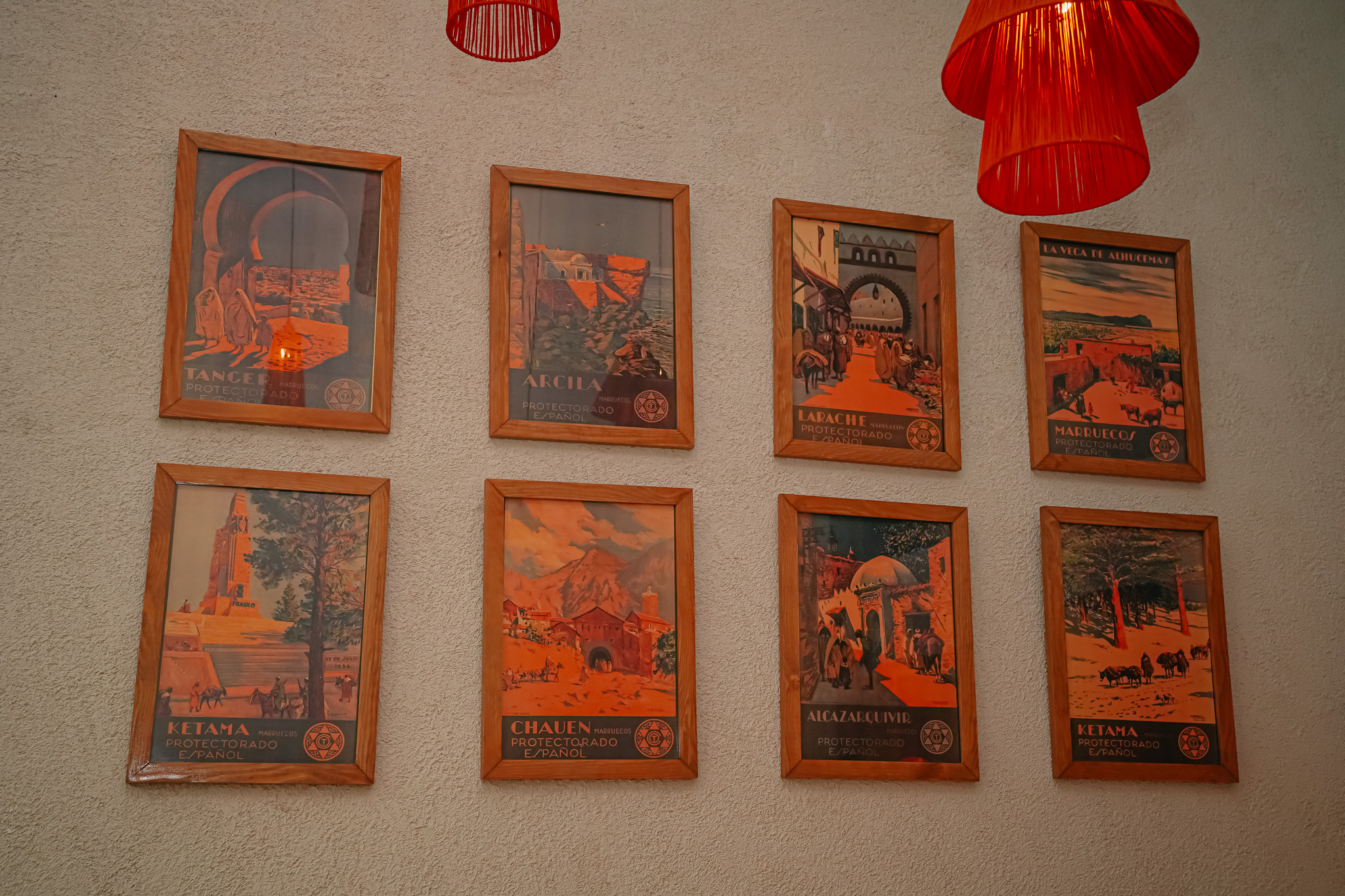 Mur de posters vintage de Tanger, Arcila, Larache et Chefchaouen à l'entrée du bistrot